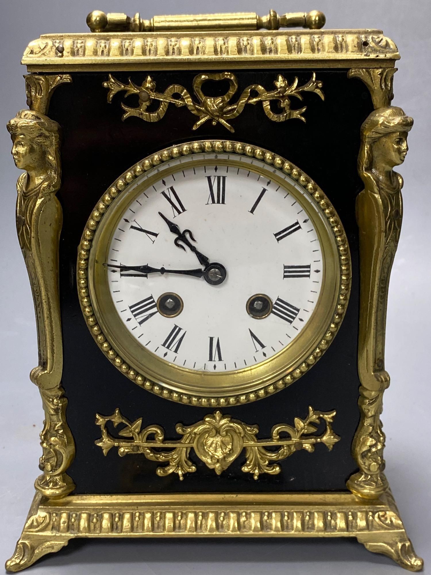 A French ebonised mantel clock with cast brass mounts, 9cm convex enamel dial, bell striking movement, height 27cm incl. handle